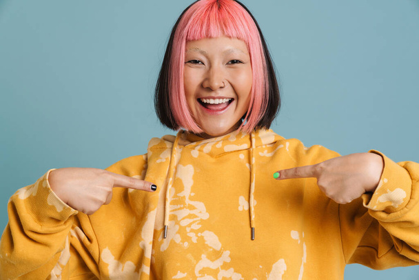 Asian girl with pink hair and piercing pointing fingers at herself isolated over blue background - Fotografie, Obrázek