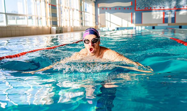 Nadador en la piscina. Un atleta masculino se dedica a nadar en una piscina deportiva. - Foto, imagen
