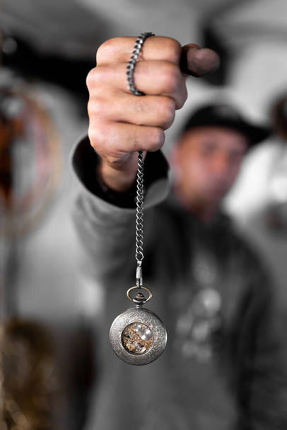 A craftsman jeweler is picking up a handmade pocket clock holding the chain. Concept of craft work - Фото, зображення