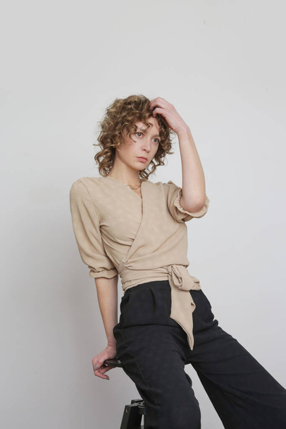 Series of studio photos of young female model in beige and black linen outfit. - Фото, изображение