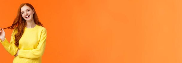 Insouciant beau, souriant toothy rousse femme, fille aux cheveux roux rire comme des amis bavards, rouler la boucle sur les cheveux, incliner la tête et sourire joyeusement, avoir la conversation, fond orange
. - Photo, image