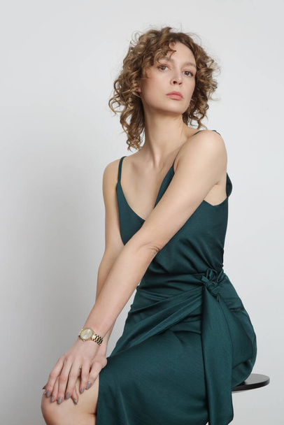Жіноча модель в зеленому шовковому верху і загорнута міді спідниця. Стильний монохромний літній одяг. Студійний знімок моди
. - Фото, зображення