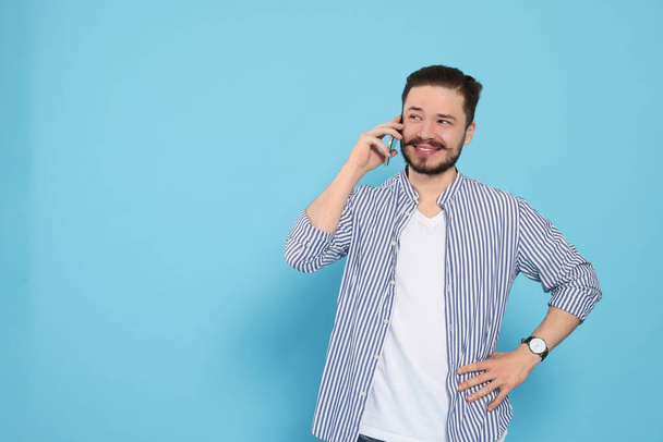 Happy man talking on smartphone against light blue background. Space for text - Photo, Image