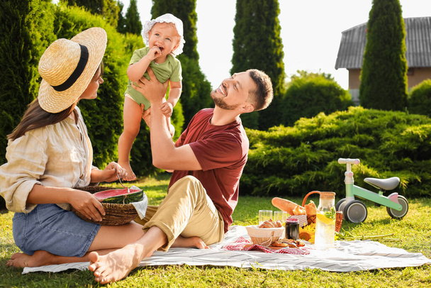 Happy family having picnic in garden on sunny day - Foto, imagen