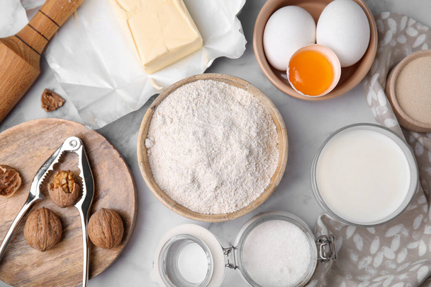 Bowl of flour and other ingredients in white table, flat lay - Fotoğraf, Görsel