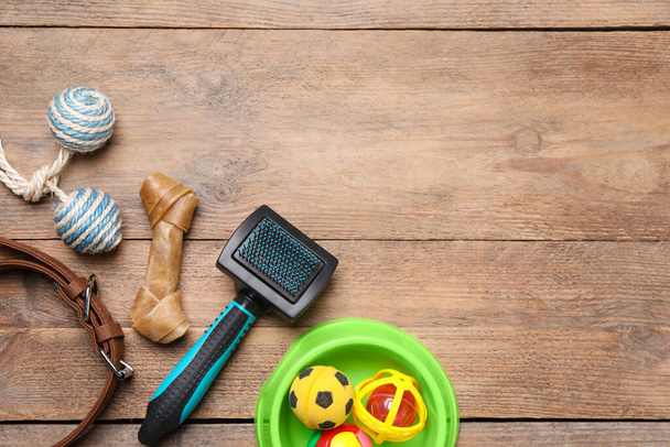 Домашние игрушки, миска и принадлежности на деревянном столе, плоская раскладка. Пространство для текста - Фото, изображение