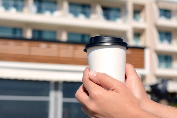 Woman holding takeaway coffee cup outdoors, closeup. Space for text - Photo, image