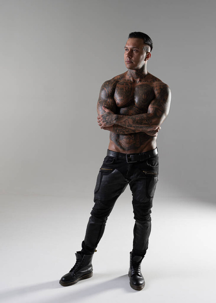 Giovane bel bodybuilder posa, atleta mostra bodybuilding posa. caldo tatuato uomo con bel corpo mostra i suoi muscoli in studio - Foto, immagini