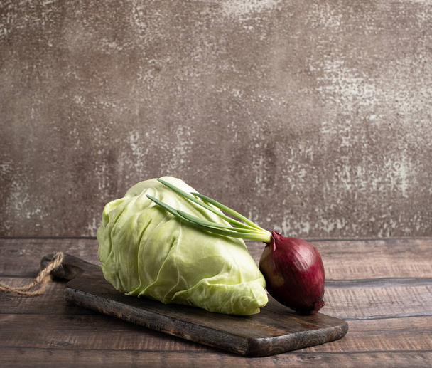Cone head cabbage and onion for dietary, vegan on a brown background - Photo, Image