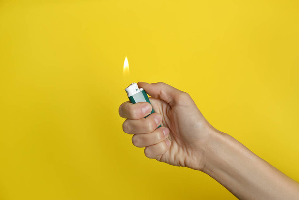 Woman holding green lighter on yellow background, closeup - Photo, Image