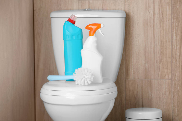 Bottles of cleaning products and brush on toilet bowl indoors - Fotografie, Obrázek