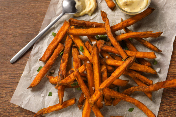 Delicious sweet potato fries and sauce on wooden table, top view - Φωτογραφία, εικόνα