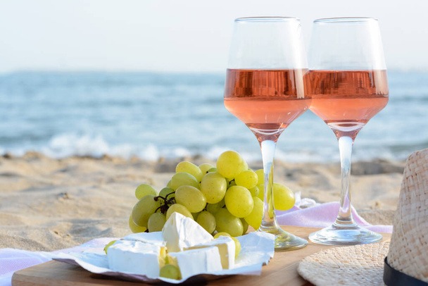 Glasses with rose wine and snacks on sandy seashore, closeup. Space for text - Valokuva, kuva