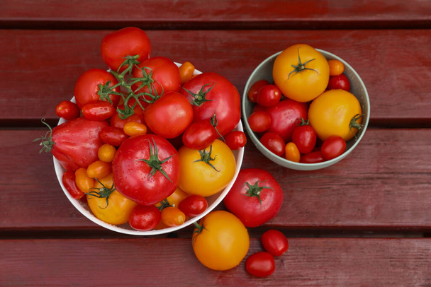 Bowls with fresh tomatoes on wooden table, flat lay - Fotoğraf, Görsel