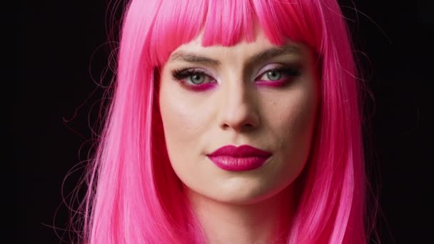 Stilvolle Glamour-Person mit pinkfarbener Perücke posiert im Studio, fühlt sich selbstbewusst und unbeschwert über dem Hintergrund. Attraktive sinnliche Frau mit trendiger, süßer Frisur, die elegante und natürliche Emotionen zeigt. - Filmmaterial, Video