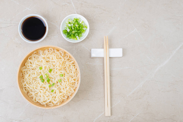 White bamboo plate (bowl) with egg noodles and plates with ingredients for it on a light background. Asian traditional fast food - Photo, Image