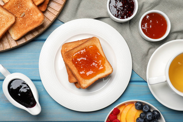 Tasty toasts served with different jam on light blue wooden table, flat lay - Foto, afbeelding