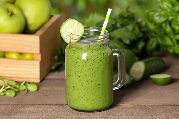 Mason jar of fresh green smoothie and ingredients on wooden table outdoors - Fotoğraf, Görsel
