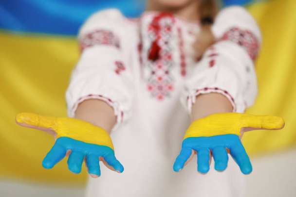 Little girl with painted hands near Ukrainian flag, closeup. Love Ukraine concept - Φωτογραφία, εικόνα