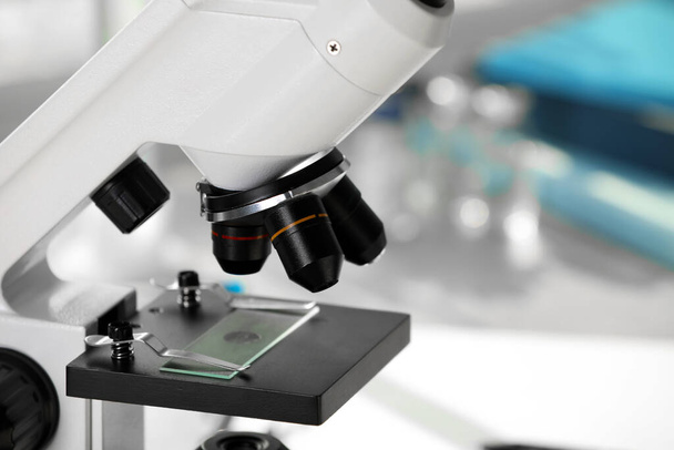 Modern medical microscope with glass slide on blurred background, closeup. Laboratory equipment - Φωτογραφία, εικόνα