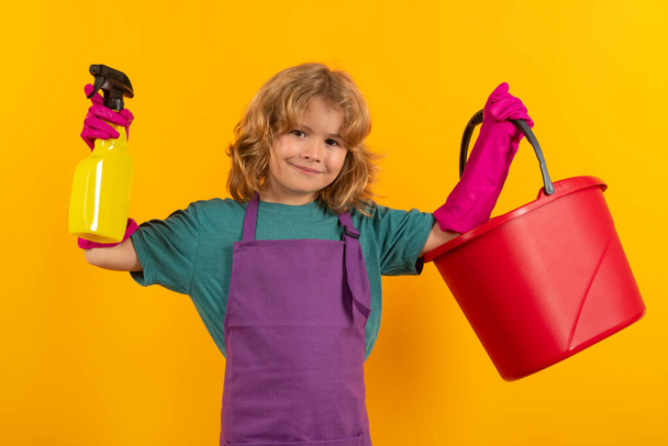Kind reinigt thuis concept. Kind schoonmaken met dweil om te helpen met huishoudelijk werk. Kleine schattige jongen vegen en schoonmaken, geïsoleerd op studio kleur achtergrond - Foto, afbeelding