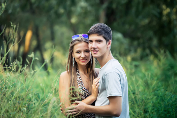 Um belo jovem casal socializa na natureza. Jovens amantes em um encontro em um parque da cidade. Bonito cara abraça uma garota em um prado - Foto, Imagem