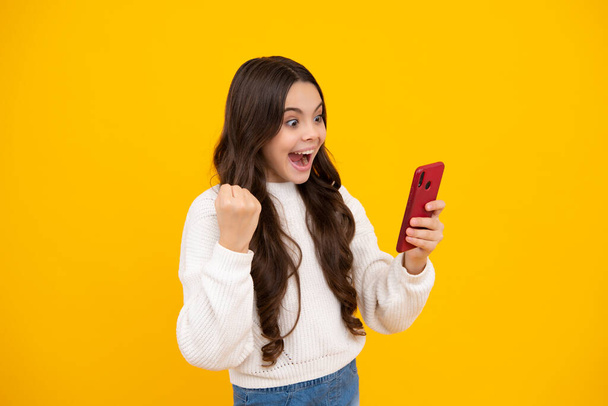 Excited teenager girl child using mobile phone, chatting on web. Mobile app for smartphone. Children lifestyle concept - Fotó, kép