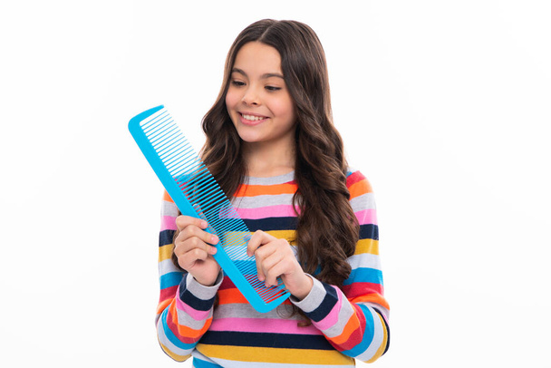 Κοριτσάκι με βούρτσα που χτενίζει τα μαλλιά. Κορίτσι που φροντίζει τα μαλλιά και το χτένισμα. Χαρούμενο πρόσωπο κοριτσιού, θετικά και χαμογελαστά συναισθήματα - Φωτογραφία, εικόνα