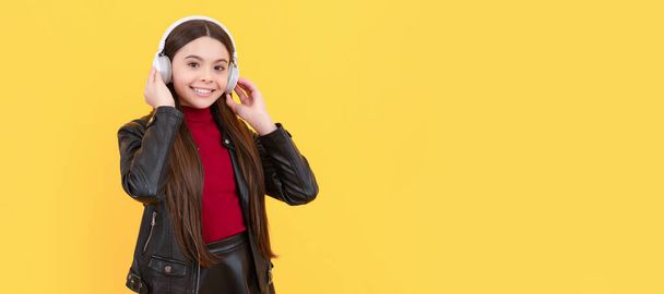 Lächelndes Kind mit Kopfhörern auf gelbem Hintergrund, Bildung online. Kinderporträt mit Kopfhörer, horizontales Plakat. Mädchen hören Musik, Banner mit Kopierraum - Foto, Bild