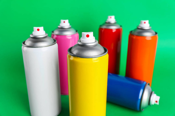 Colorful cans of spray paints on green background - Foto, Imagen