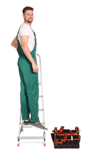 Worker in uniform on metal ladder against white background - Photo, image