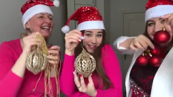 Spousta smíchu radost z úsměvů Tři ženy slaví Nový rok, mají na sobě červený klobouk se sněhovými vločkami v rukou Vánoční stromeček hračky párty komunikace láska přátelství ženy tanec - Záběry, video