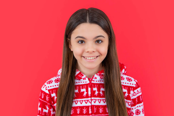 Vrolijk kerstfeest. glimlachend tienermeisje in rode kerstkleren in de studio. tiener kerst meisje geïsoleerd op rode achtergrond. - Foto, afbeelding