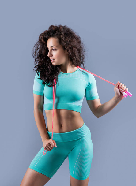 fitness woman in sportswear with skipping rope at studio. fitness woman in sportswear hold skipping rope isolated on grey background. fitness and sport. - Photo, Image