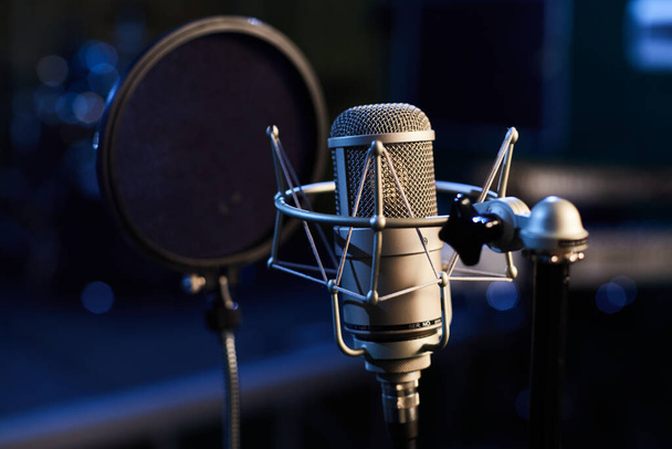 Microphone with pop shield closeup on the background of professional recording studio. Microphone stand with condenser for records vocals, speakers and sound of musical instrument. High quality photo - Fotografie, Obrázek