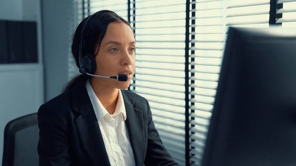 Competent female operator working on computer and talking with clients. Concept relevant to both call centers and customer service offices. - 写真・画像