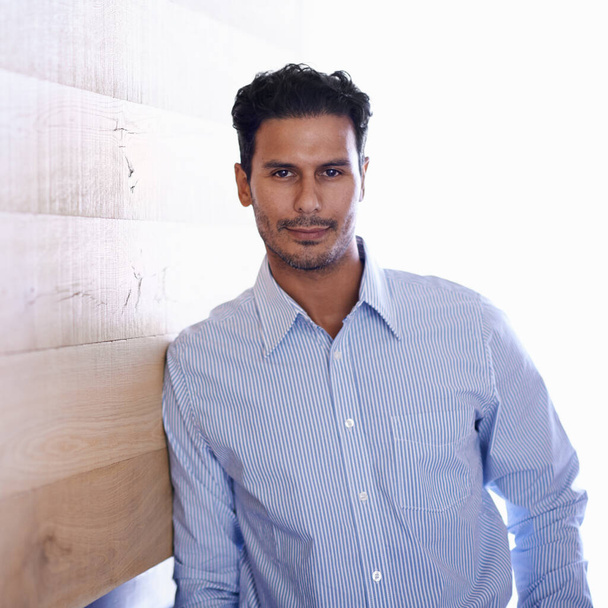 Hes the ultimate businessman. Portrait of a handsome young businessman leaning against a wooden wall - Foto, imagen