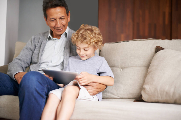 Der Schatten des Patriotismus. Ein Großvater sitzt mit seinem Enkel, während er ein digitales Tablet benutzt - Foto, Bild