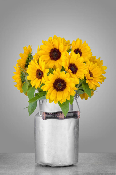 Aluminum can with a bouquet of sunflowers on a gray background. - Photo, Image