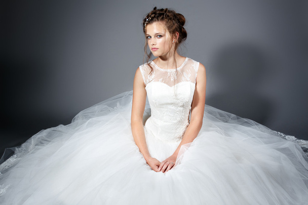 Beautiful young bride in a wedding white dress on the gray stylish background - Zdjęcie, obraz