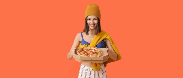 Beautiful woman with tasty pizza on orange background - Foto, afbeelding
