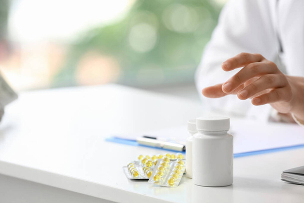 Naislääkäri ottaa vitamiineja pöydästä klinikalla, lähikuva - Valokuva, kuva