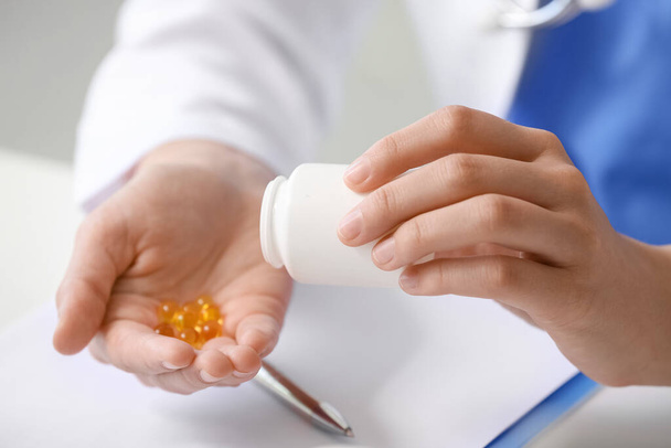 Vrouwelijke arts met vitaminen zitten aan tafel in kliniek, closeup - Foto, afbeelding