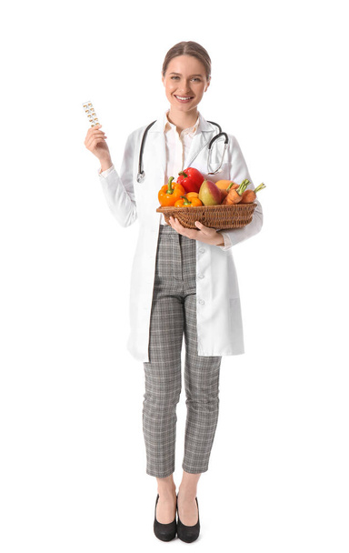 Médico femenino con vitaminas y alimentos saludables sobre fondo blanco - Foto, Imagen