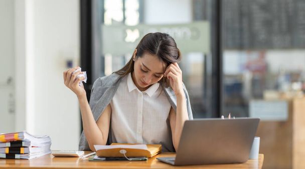 疲れた若いビジネスの肖像アジアの女性は、オフィスで書類税のラップトップコンピュータで動作します。悲しい、不幸な、心配、うつ病、または従業員の生活ストレスの概念 - 写真・画像