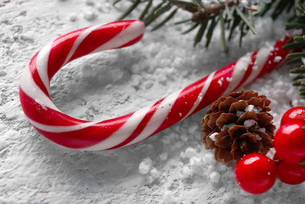 Sweet candy cane, Christmas decorations and snow on light background, closeup - Φωτογραφία, εικόνα