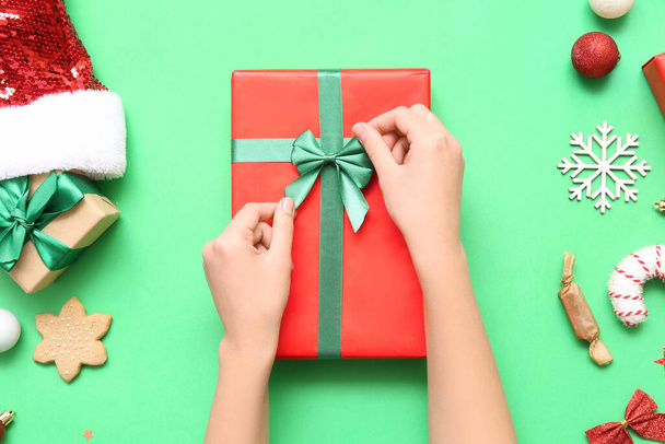 Femme avec cadeaux de Noël, friandises et décoration sur fond vert - Photo, image