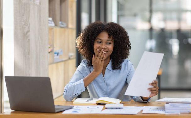 Успешный американский бухгалтер-афроамериканец, деловая женщина, работает с документами на ноутбуке в офисе. финансирование инвестиционной экономики и маркетинговых исследований. - Фото, изображение