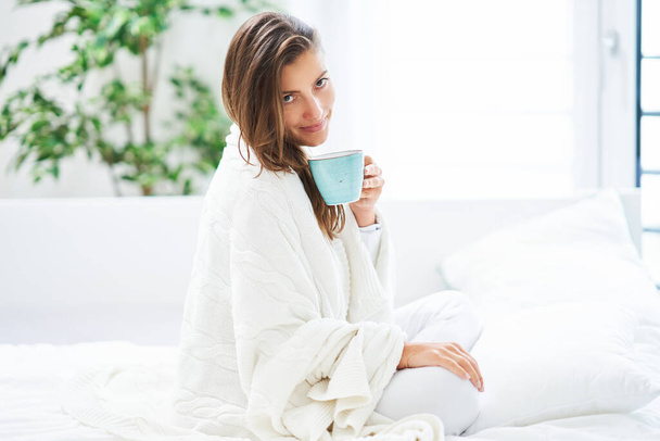 Jeune femme agréable au lit avec café ou tasse de thé. Photo de haute qualité - Photo, image