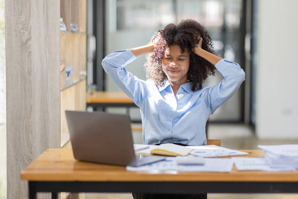 疲れた若いビジネスアフリカ系アメリカ人女性の肖像は、オフィスで書類税のラップトップコンピュータで動作します。悲しい、不幸な、心配、うつ病、または従業員の生活ストレスの概念  - 写真・画像